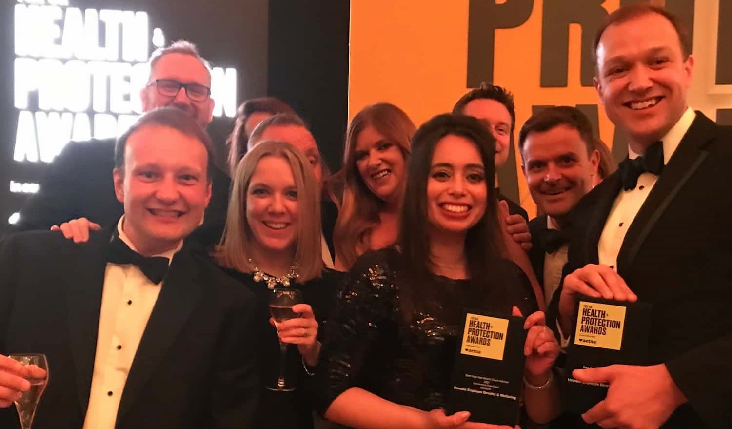Howden's Employee Benefits and Wellbeing Team holding an award backstage