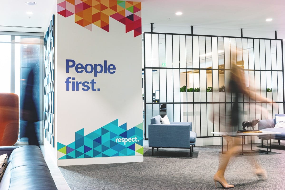 People passing a sign saying "People first" in a Howden office
